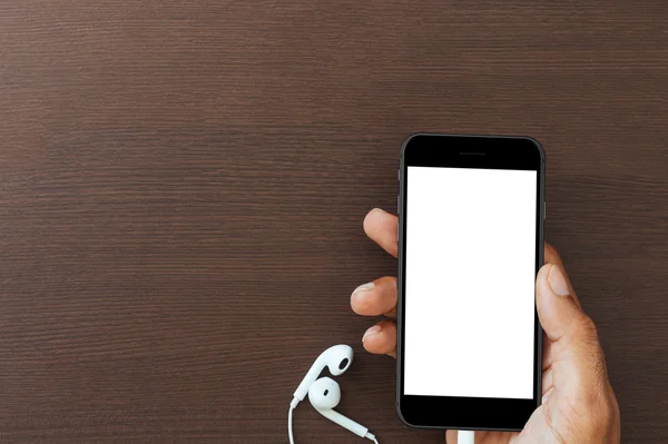 Рука тримає телефон білий екран на дерев'яному столі, макет нового розумного фені — стокове фото