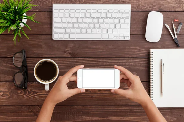 Mão segurando telefone horizontal mostrando tela em branco do telefone no trabalho — Fotografia de Stock