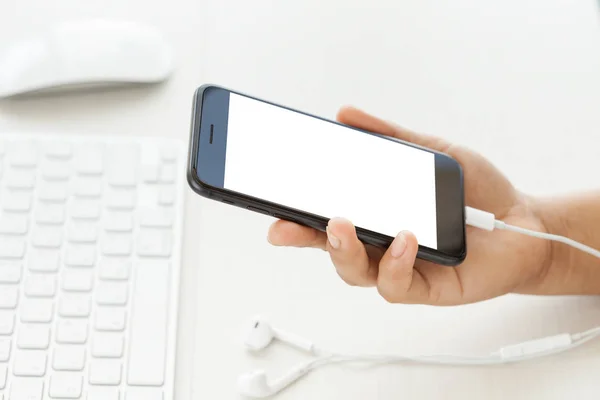 Close-up hand holding phone  mobile showing white screen on desk — Stock Photo, Image