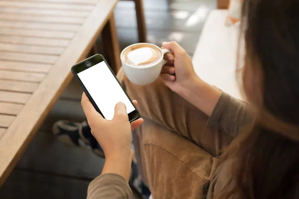 Mujer sosteniendo teléfono y café en la cafetería — Foto de Stock