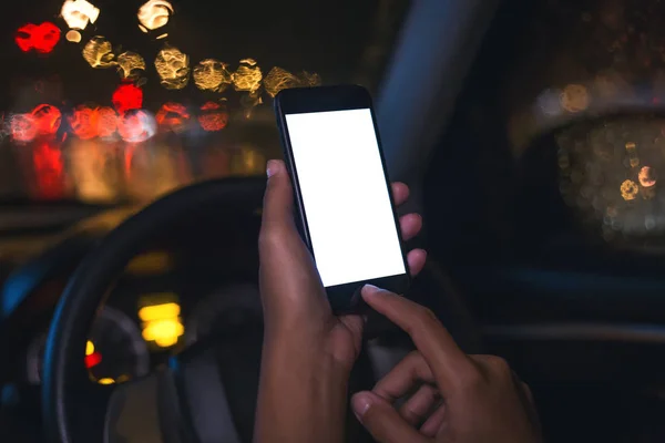 Mano de cerca utilizando el teléfono dentro del coche en la noche en la ciudad —  Fotos de Stock