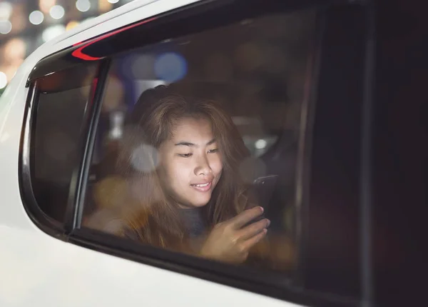 Mulher usando telefone dentro do carro na cidade à noite — Fotografia de Stock