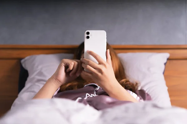 Mulher usando telefone na cama depois de acordar — Fotografia de Stock