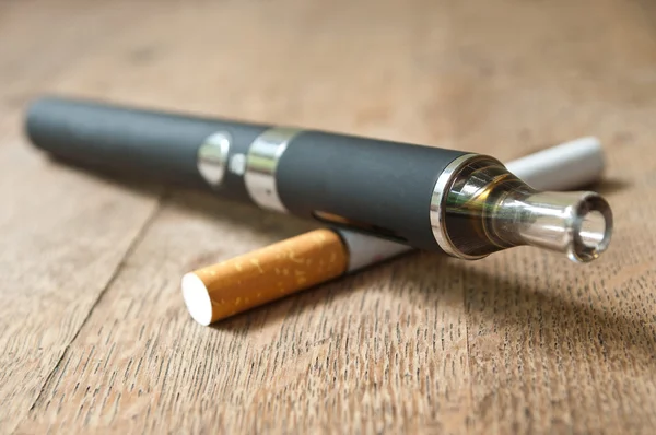 Schwarze E-Zigarette mit Zigarette auf Holzgrund — Stockfoto