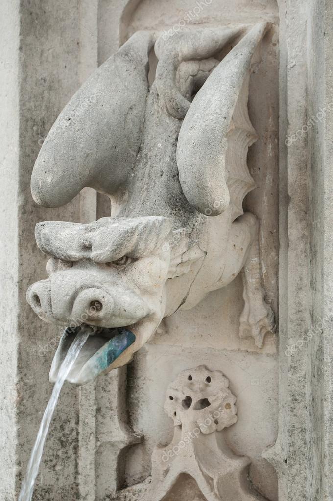Gargoyle in a fountain spitting water by mouth — Stock Photo