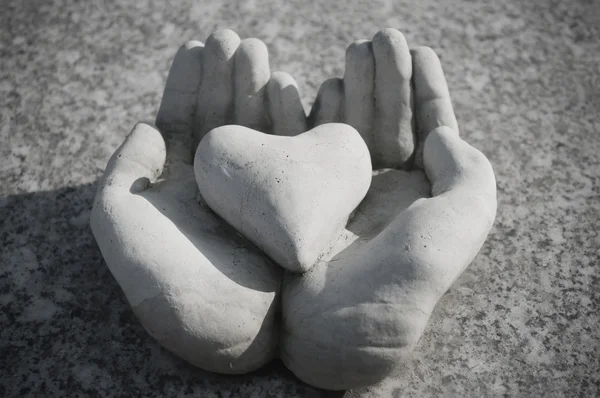 Coração em mãos apedrejadas no cemitério em um túmulo — Fotografia de Stock