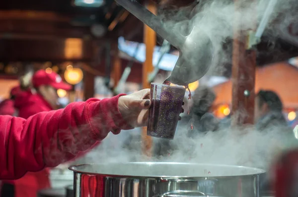 Close-up de mulher dando uma xícara de vinho quente no mercado de natal — Fotografia de Stock