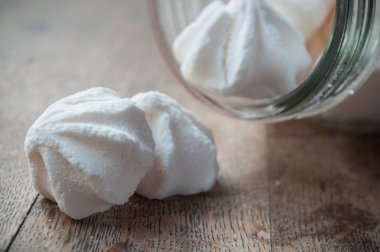 Meringues cam kapsayıcıdan ahşap masa arka plan üzerine düşmek.