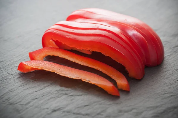 Pimientos rojos en rodajas sobre fondo de pizarra — Foto de Stock