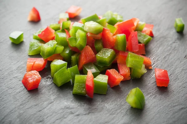 Cubos de pimientos rojos y verdes sobre fondo de pizarra — Foto de Stock