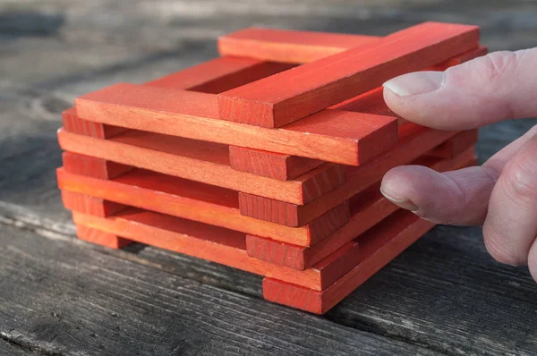 Mano tratar de quitar pieza de ladrillo de madera de juego de construcción en el aire libre — Foto de Stock