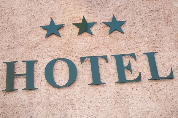 Sinalização do hotel com três estrelas na parede apedrejada — Fotografia de Stock