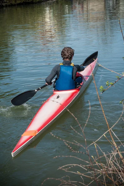 Homme flotte sur un bateau rouge dans les eaux calmes rivière — Photo