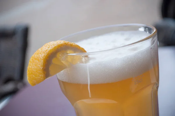 Glas Bier auf dem Tisch mit Zitronenscheiben — Stockfoto