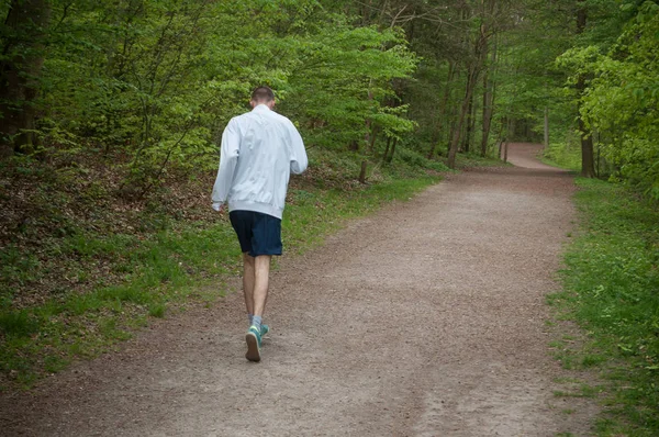 Hombre corriendo en el bosque en primavera — Foto de Stock