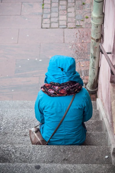 Kvinna placering på trappor med blå kappa med huva — Stockfoto