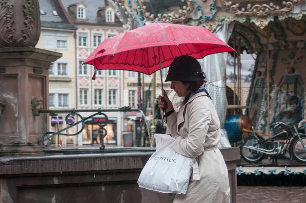 Porträt einer Frau mit rotem Regenschirm auf Kopfsteinpflaster Hauptplatz der Stadt — Stockfoto