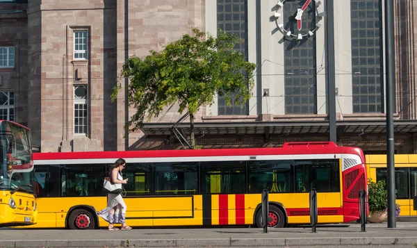 Woman walking with phone in front of Train station facade with bus — Stock Photo, Image