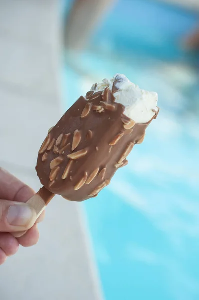 Ice cream eskimo in hand near swimming pool — Stock Photo, Image
