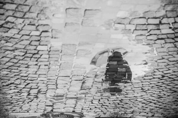 Reflection of man with umbrella on cobbles place in the city — Stock Photo, Image