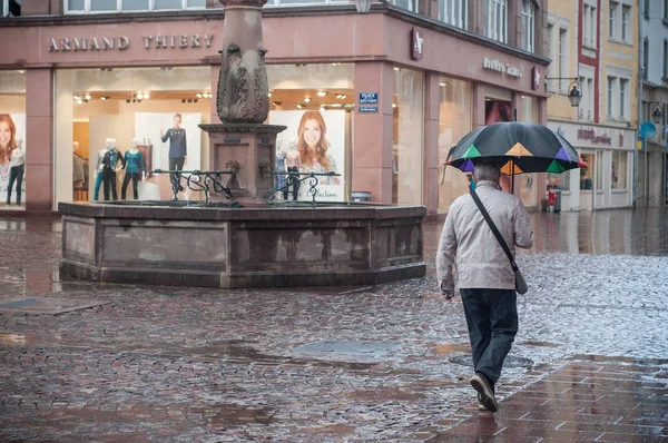 Портрет человека с зонтиком на булыжнике с фонтаном в городе — стоковое фото