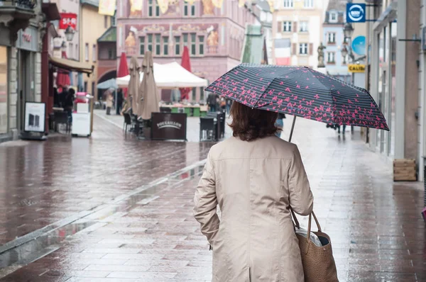Женщина ходит по улице с зонтиком — стоковое фото