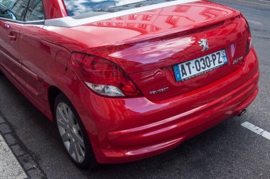 Kırmızı Peugeot 206 Cc sokakta park edilmiş.