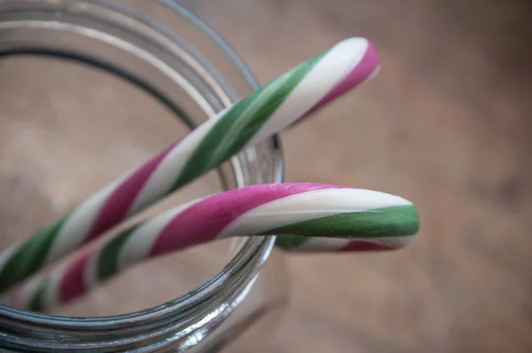 Bastones de caramelo en recipiente de vidrio sobre fondo de madera —  Fotos de Stock