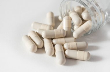  kapsül ve şişe beyaz zemin üzerine düşen ilaç tablet