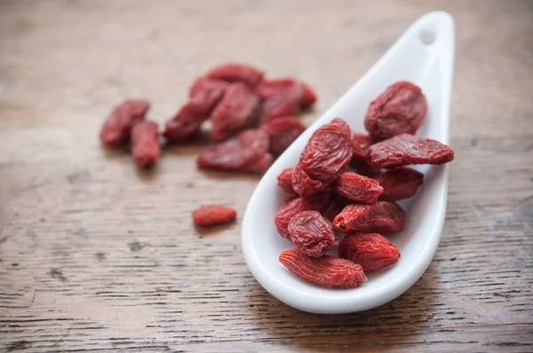 Goji bagas em colher chinesa no fundo da mesa de madeira — Fotografia de Stock