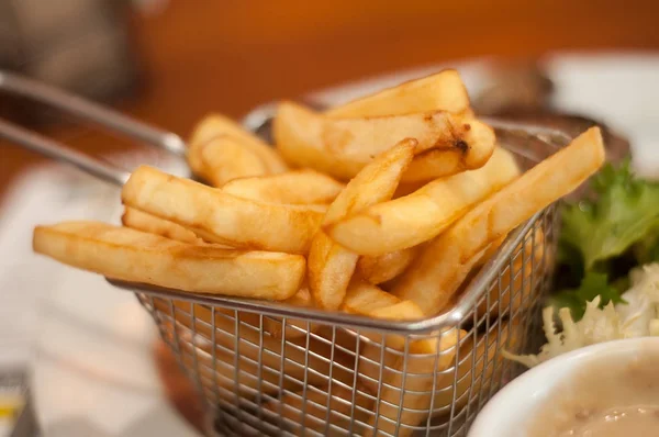 Batatas fritas em pequena cesta metálica em um restaurante prato — Fotografia de Stock