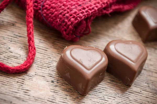 Chocolates en forma de corazón sobre fondo de mesa de madera — Foto de Stock