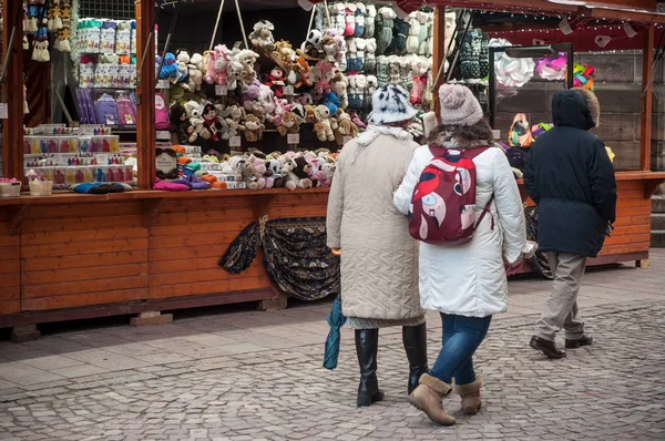 Personas con sombrero de lana caminando en el mercado de Navidad frente a la tienda de juguetes blandos — Foto de Stock