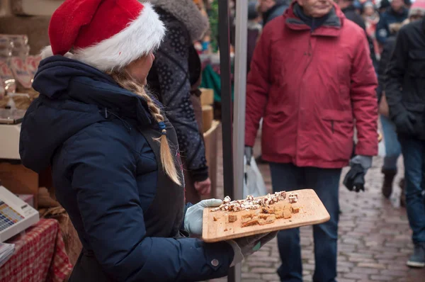 Vrouw met KERSTMUTS proeverij van ontbijtkoek op houten snijplank op de kerstmarkt — Stockfoto