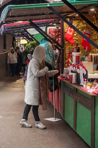 Mujer de pie frente a la tienda tradicional en el mercado de Navidad —  Fotos de Stock