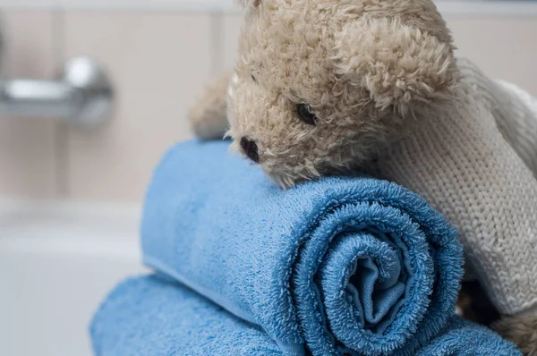 Medvídek na válcované modré osušky v koupelně — Stock fotografie