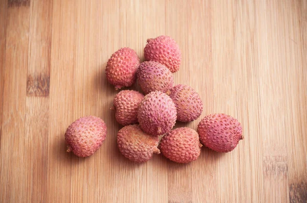 Lychees on wooden cutting board in bamboo texture — Stock Photo, Image