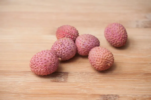 Lychees on wooden cutting board in bamboo texture — Stock Photo, Image