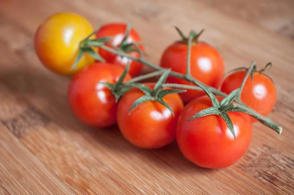 Tomates cereja em tábua de corte de madeira — Fotografia de Stock