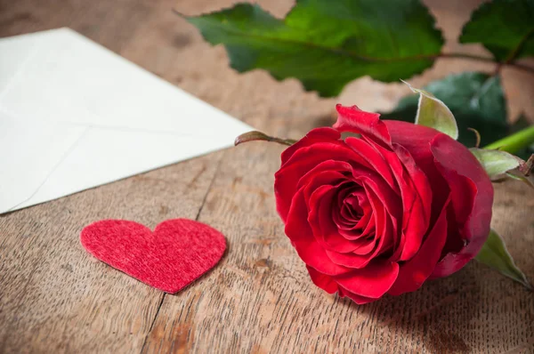 Rosa roja y regalo sobre fondo de mesa de madera — Foto de Stock