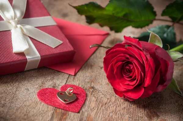 Rosa roja y regalo sobre fondo de mesa de madera — Foto de Stock