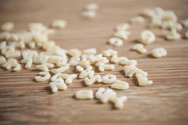 Pasta del alfabeto sobre fondo de madera — Foto de Stock