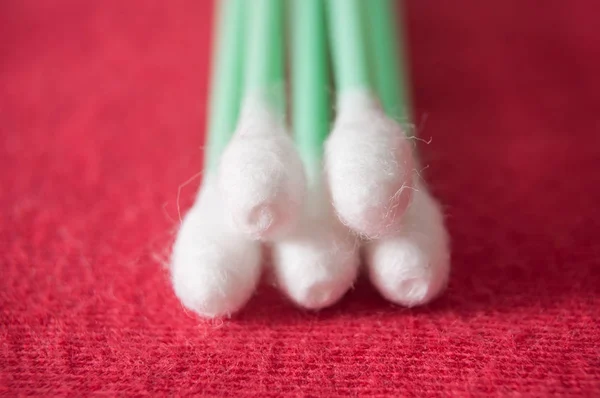 Green cotton swabs on red background — Stock Photo, Image