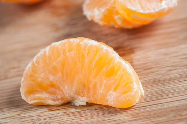 Mandarina pelada sobre fondo de tabla de cortar de madera — Foto de Stock