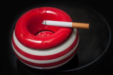 siyah zemin üzerine kırmızı kül tablası üzerinde Sigara 