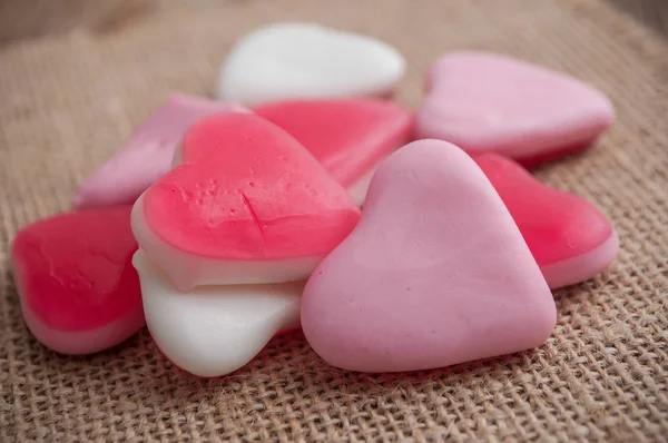 Caramelos con forma de corazón sobre fondo hessiano — Foto de Stock