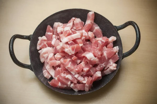 pork cubes in mini stove on wooden background