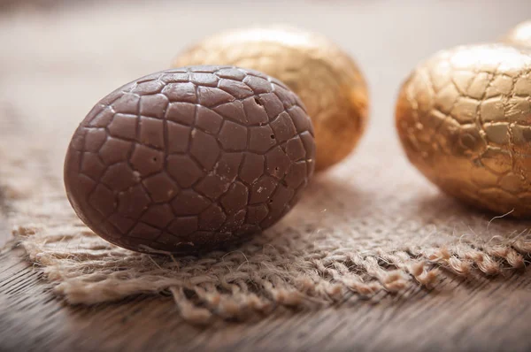 Chocolade paaseieren in gouden papier op houten tafel — Stockfoto