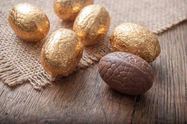 Chocolade paaseieren in gouden papier op houten tafel — Stockfoto