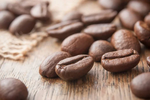 Koffiebonen op houten tafel achtergrond — Stockfoto